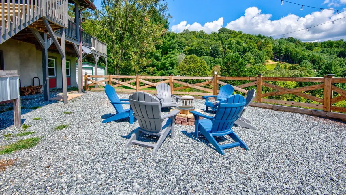 A welcoming fire pit area surrounded by Adirondack chairs, set against a backdrop of natural landscape. The scene evokes evenings spent outdoors, sharing stories and enjoying the warmth of a fire with friends or family.